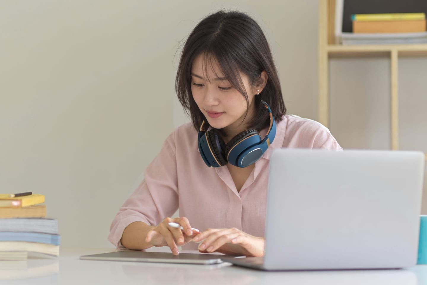 목에 헤드폰을 건 채 노트북 앞에서 태블릿에 펜으로 적어 가는 온라인 수업 장면