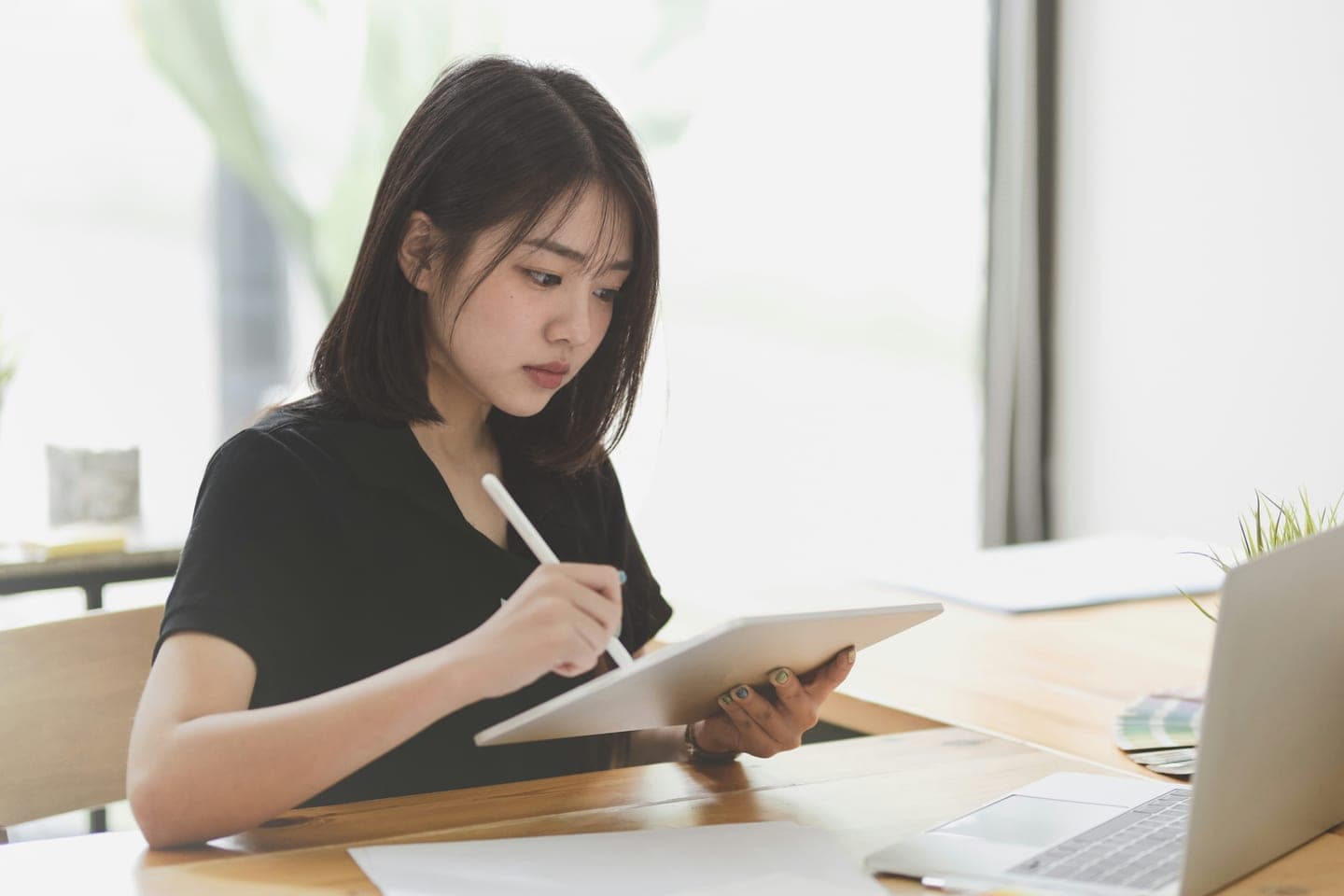 나무 책상에서 노트북을 옆에 두고 태블릿에 펜으로 공부할 순서를 적는 장면
