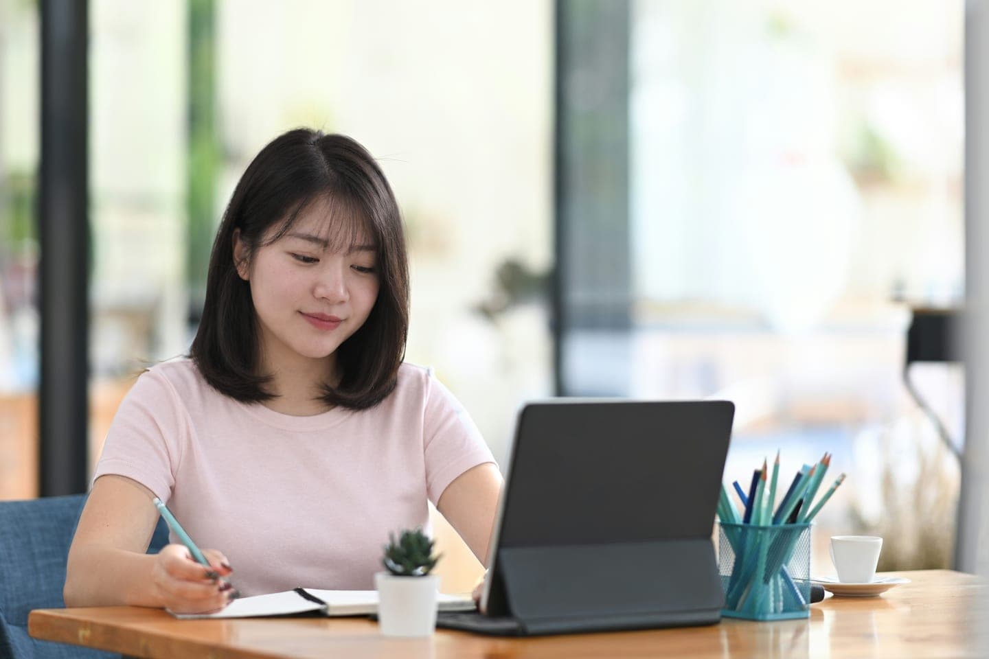 키보드를 붙인 태블릿 옆에서 공책에 공부 계획을 적는 장면